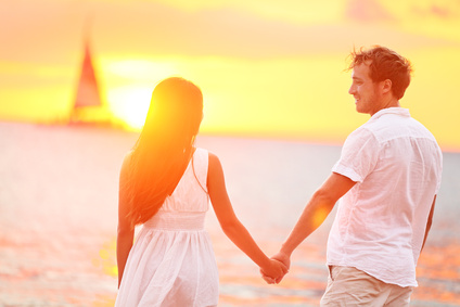 Couple in love happy at romantic beach sunset. Young interracial couple holding hands having romance and fun outside walking on beach during summer holidays vacation travel together. Enjoying sunshine